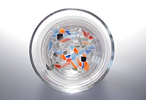 A glass of water in which small and colorful pieces of plastic float.
