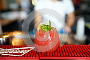 A glass of Watermelon cocktail with lemon and mint leaves on blurred background and copy space.