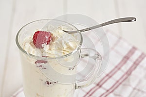 Glass with whipped cream and raspberries on a checkered napkin