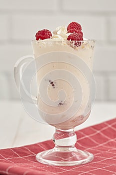 Glass with whipped cream and raspberries on a checkered napkin