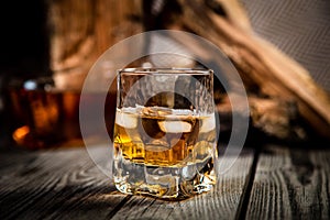 glass of whiskey and a bottle of whiskey on a wooden background