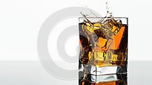 Glass of Whiskey or Brandy. Splash in a Glass on white background. Alcohol Drink. Clear ice in cube shape.