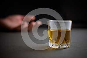 Glass of whiskey or cognac or alcohol drink, hand of a drunk man