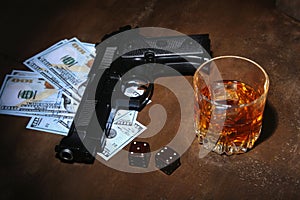 Glass of whiskey or cognac, gun, playing cards with money on the black mirror table. The concept of criminal.