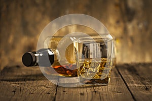 A Glass of whiskey and empty Bottle of whiskey on a wooden background