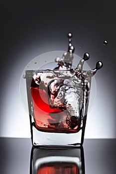 Glass of whiskey with falling ice on a black background
