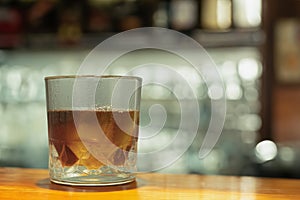 A glass of whiskey with ice. Background with copy space. A glass of alcohol on the bar counter