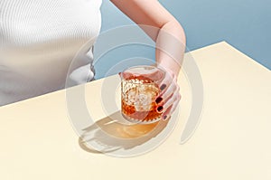 Glass with Whiskey and Ice Cube in Woman Hand on Table on Blue Background. Modern Isometric Style. Creative Concept