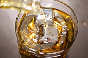 Glass of Whiskey with ice cube on wooden table