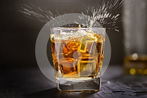 Glass of Whiskey with ice cube on wooden table