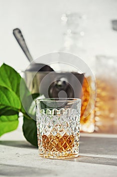 Glass of whiskey with ice cubes, ice bucket and carafe close up