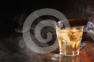 Glass of whiskey with ice cubes and smoldering cigar on black background. Space for text