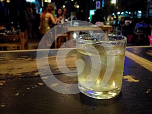 Glass of whiskey and ice cubes on wooden table