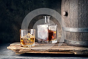 Glass of whiskey with ice decanter and barrel