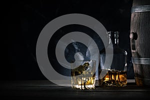 Glass of whiskey with ice, decanter and a wooden barrel