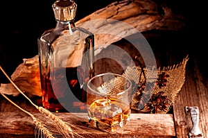 Glass of whiskey with ice decanter on wooden table