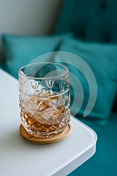 Glass with whiskey with ice on the edge of the table