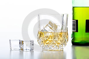 Glass of whiskey and ice on white background