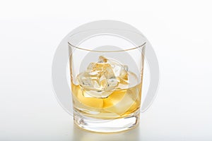 Glass of whiskey and ice on white background