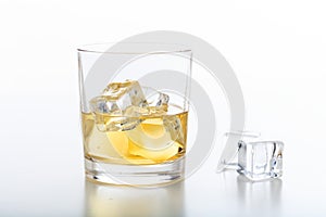 Glass of whiskey and ice on white background
