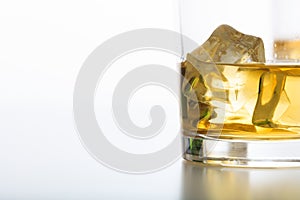 Glass of whiskey and ice on white background