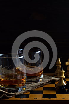 Glass of whiskey with ice on a wooden background.