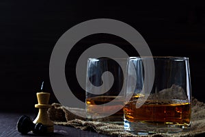 Glass of whiskey with ice on a wooden background.