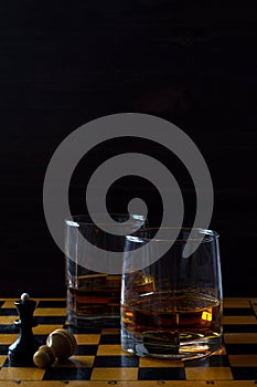 Glass of whiskey with ice on a wooden background.