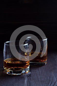 Glass of whiskey with ice on a wooden background.