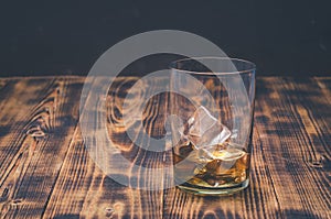 Glass of whiskey with ice on a wooden table. With copyspace. Transparent glass with alcohol with ice. Selective focus