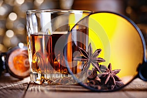 Glass of whiskey, magnifying glass, anise and cinnamone photo