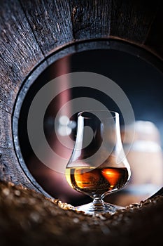 A glass of whiskey in oak barrel