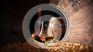 Glass of whiskey in an old wooden oak barrel