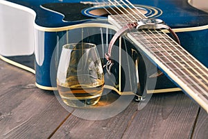 Glass of whiskey on the table and guitar