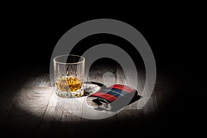 Glass of whisky and a hip flask against a black background copy space