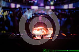 Glass with whisky with ice cube inside on dj controller at nightclub. Dj Console with club drink at music party in nightclub with