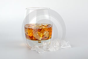 Glass of whisky and ice cubes on white background