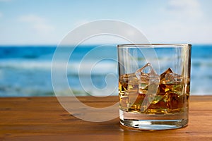 Glass of Whisky With Ice on a Wooden Table Against The Sea