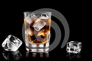 glass of whisky on the rocks with ice cubes isolated on black surfce with reflections