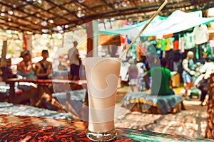 Glass of white creamy milk drink Banana Lassi on table of cafe in Goa, India.