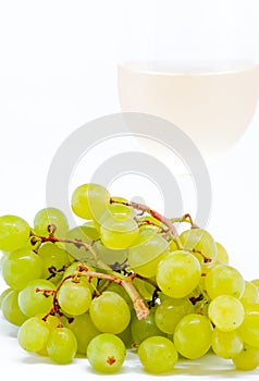 Glass with white dry wine and white grapes on white