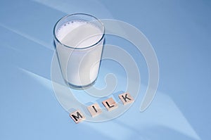 Glass of white milk isolated on blue background, close up. Dairy product concept, copy space
