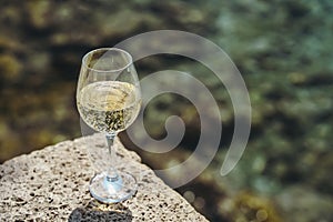 Glass of white wine against the background of the Mediterranean beach and the sea in a tourist town in the summer under
