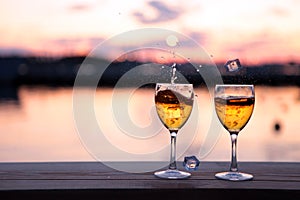 Glass of white wine against sunset. Beautiful summer evening sea view