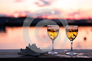 Glass of white wine against sunset. Beautiful summer evening sea view