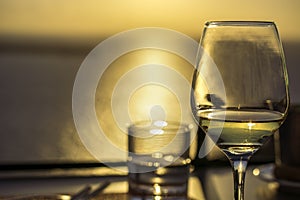 Glass of white wine against sunset with sea in background