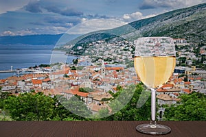 Glass of white wine against view from above on Senj town, Croatia. View from Nehaj Fortress, fort on the hill, Velebit, Croatia
