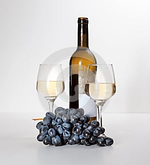 A glass of white wine, a bunch of grapes, an open bottle