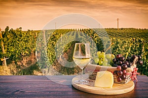 Glass of white wine in front of a vineyard at sunset