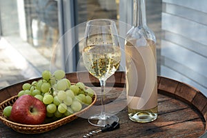 A glass of white wine with grapes on a barrel. White wine Riesling, from white grapes